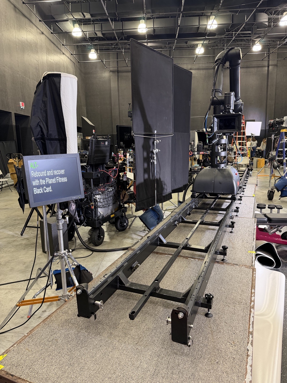Teleprompter monitor beside a motion-control camera track on a soundstage